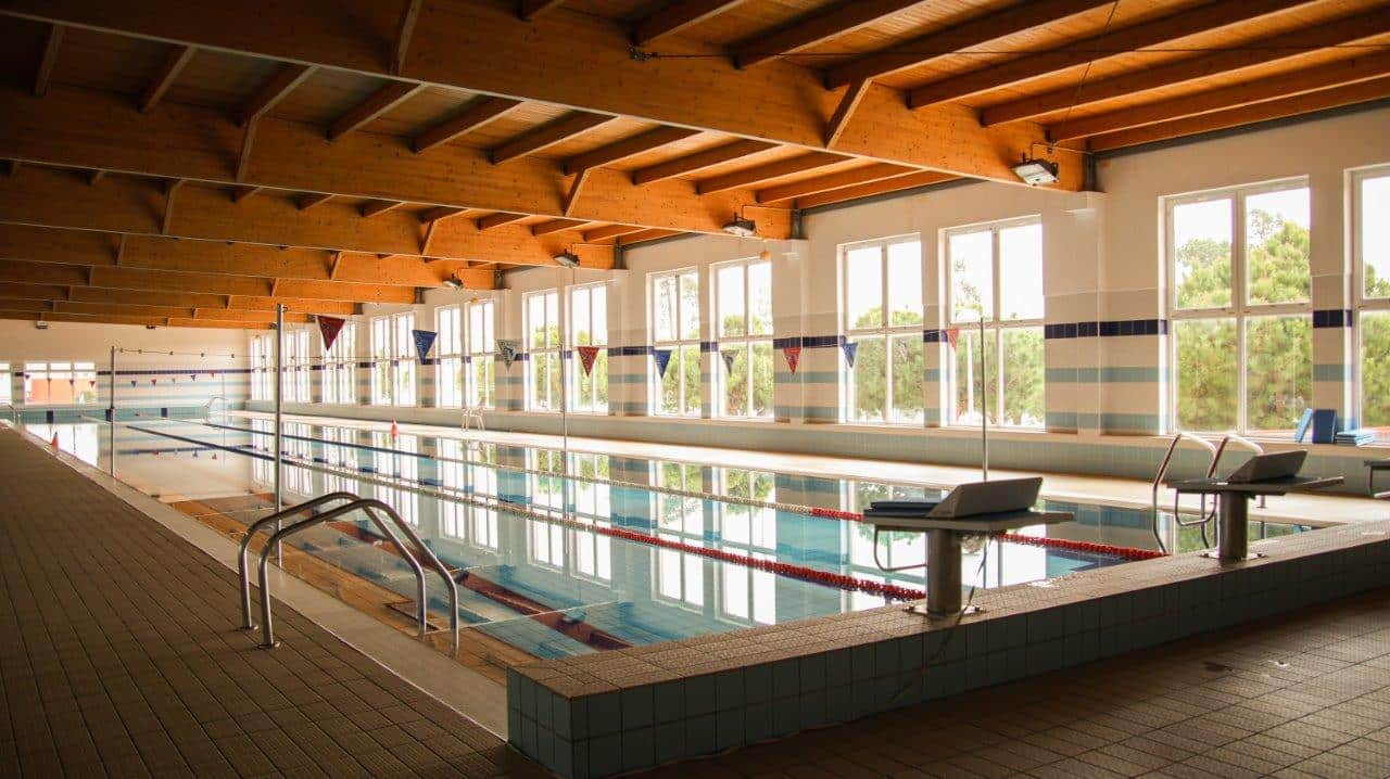 O município de Vila Real de Santo António recebeu, esta segunda-feira, dia 15 de dezembro, o Secretário de Estado do Desporto, Pedro Dias, e o diretor regional do Algarve do Instituto Português do Desporto e Juventude (IPDJ), Ricardo Pinto. A visita inseriu-se na iniciativa governamental «Portugal Real». O encontro visou demonstrar a necessidade urgente de requalificação das infraestruturas desportivas do concelho, que foram objeto de uma candidatura ao Comité Olímpico de Portugal. O investimento é ambicioso e o valor total da proposta de financiamento do município ascende aos 4 milhões de euros. O Presidente da Câmara Municipal de VRSA, Álvaro Araújo, a Vice-Presidente, Patrícia Jerónimo, e o Vereador, Fernando Horta, conduziram a comitiva pelas instalações. A mensagem da autarquia é clara: garantir o financiamento necessário para resolver o desgaste dos equipamentos e finalizar obras essenciais, de modo a preservar as condições de excelência que distinguem Vila Real de Santo António no panorama nacional. Candidaturas Municipais: Resolução de Problemas Estruturais A agenda de trabalho focou-se nos equipamentos para os quais as candidaturas são vitais. O Município de Vila Real de Santo António deverá submeter estas propostas até ao final deste ano: Pavilhão Multiusos: Foi sublinhada a necessidade de concluir esta obra inacabada. A autarquia defende que a finalização do Pavilhão permitirá, finalmente, servir a comunidade e os clubes, aumentando significativamente a capacidade do concelho para acolher modalidades de pavilhão. Piscinas Municipais: O espaço carece de obras de manutenção e modernização estrutural para garantir o conforto e a segurança dos utentes, ao mesmo tempo que se otimiza a racionalização dos recursos energéticos. Complexo Desportivo: Foi demonstrada a urgência na substituição integral dos relvados, essenciais para a formação de centenas de jovens atletas e para a prática desportiva diária e de alto rendimento. Apoio ao Associativismo e o Papel na Economia Regional A comitiva passou ainda pelo Padel Clube de VRSA e pelo Clube de Ténis de VRSA, confirmando o dinamismo do associativismo local. As candidaturas autónomas destes clubes ao PRID já foram submetidas, num processo que conta com o acompanhamento próximo da Câmara Municipal, aguardando-se a aprovação das verbas até ao final do ano. Para os responsáveis autárquicos, estes investimentos são cruciais não só para o desporto, mas também para a economia do concelho. O estatuto de Vila Real de Santo António como destino de Alto Rendimento - atraindo atletas de elite mundial durante todo o ano - é um motor essencial para a hotelaria, restauração e comércio local. Com a submissão formal das candidaturas, a Câmara Municipal de VRSA reafirma o seu papel proativo na busca de soluções de financiamento, trabalhando para valorizar o património público e oferecer melhores condições desportivas a toda a comunidade.